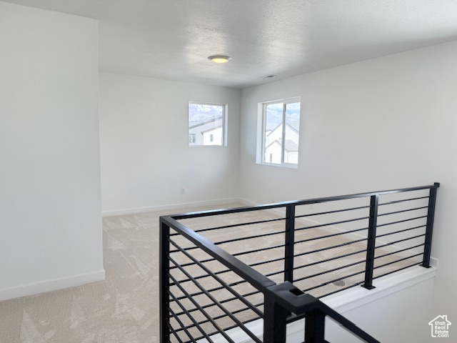 Stairway featuring carpet floors, a textured ceiling, and baseboards