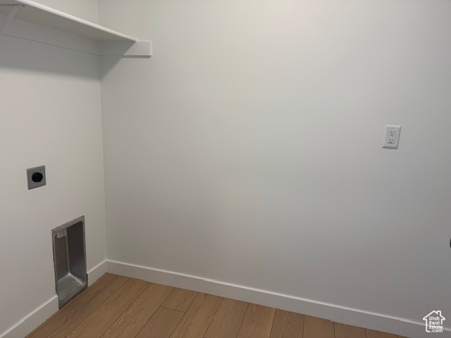 Washroom featuring hookup for an electric dryer, laundry area, baseboards, and light wood-style floors