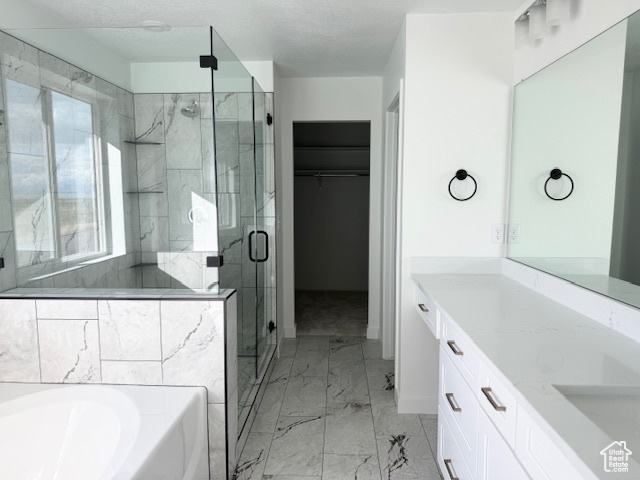 Bathroom with vanity, marble finish floor, a spacious closet, a garden tub, and a stall shower