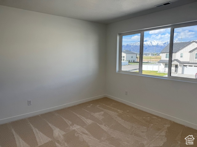 Spare room featuring visible vents, baseboards, and light carpet