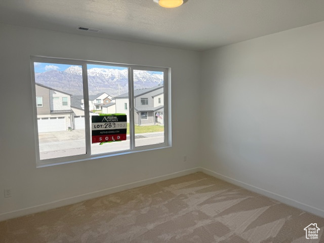 Spare room featuring carpet flooring, baseboards, visible vents, and a residential view
