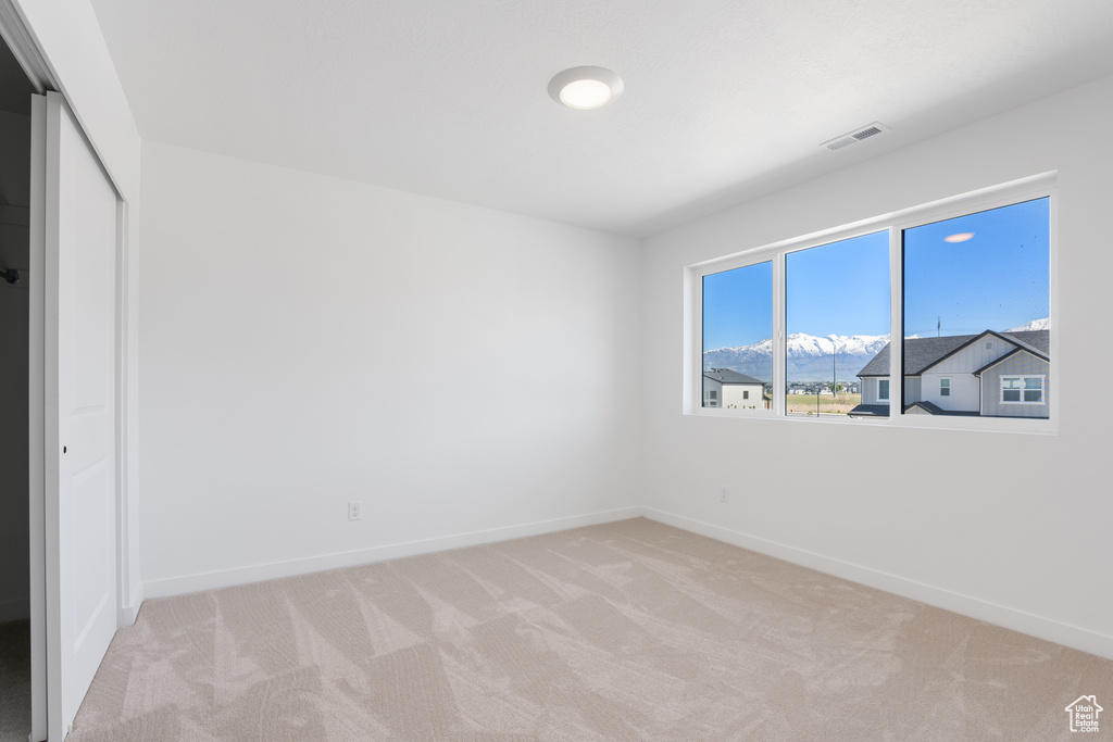 Unfurnished bedroom with light colored carpet, a closet, visible vents, and baseboards