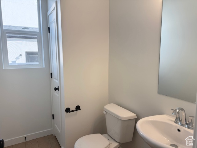 Bathroom featuring toilet, baseboards, and a sink