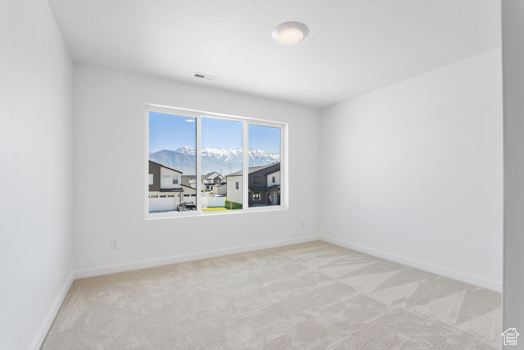 Carpeted empty room with a mountain view, baseboards, and visible vents