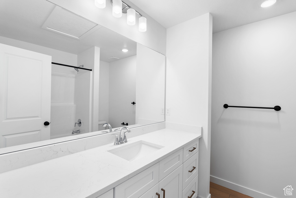 Full bathroom with wood finished floors, washtub / shower combination, baseboards, vanity, and recessed lighting
