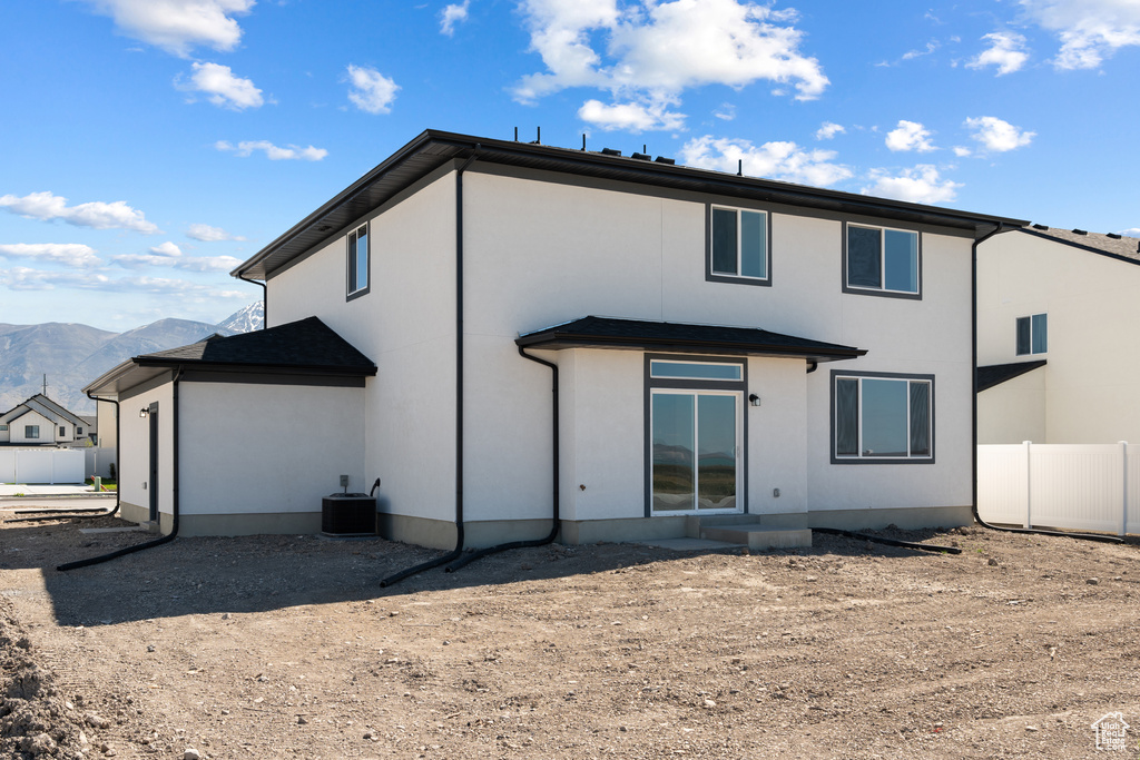 Rear view of property featuring central air condition unit, a mountain view, stucco siding, and fence