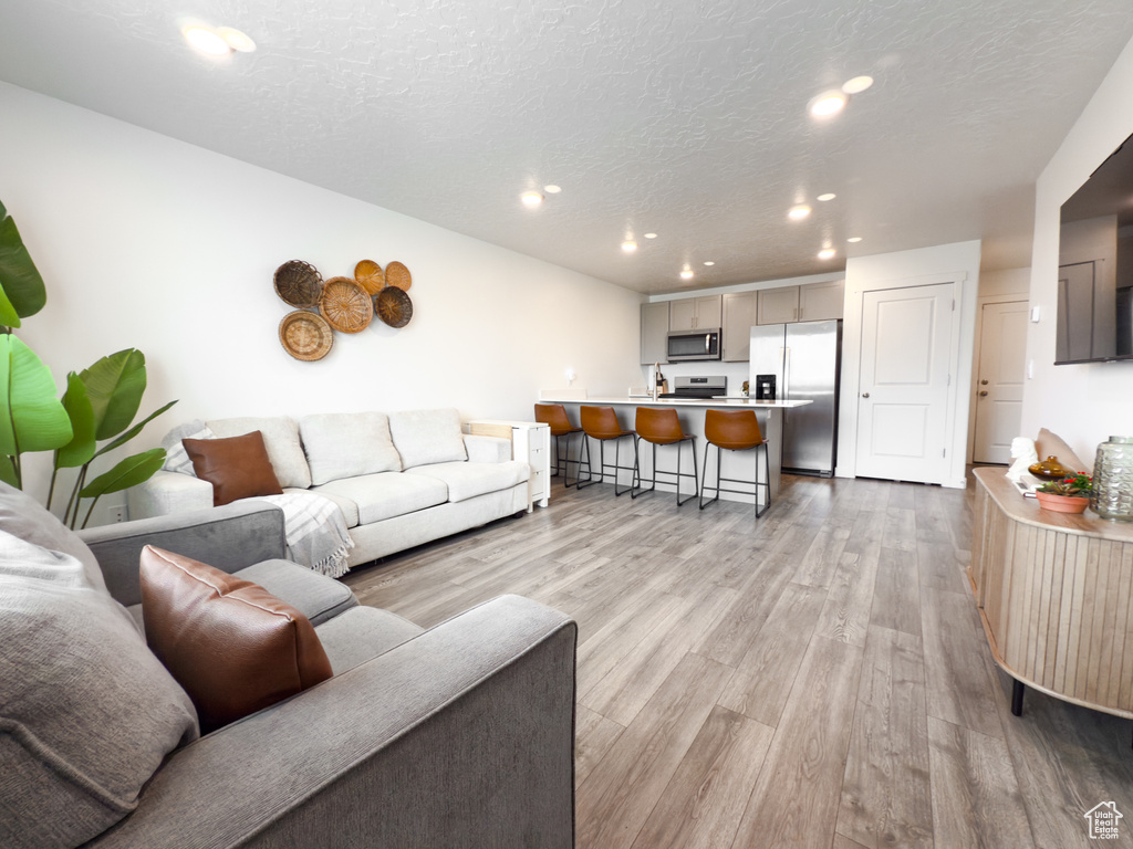Living room with light wood-type flooring, recessed lighting, and a textured ceiling