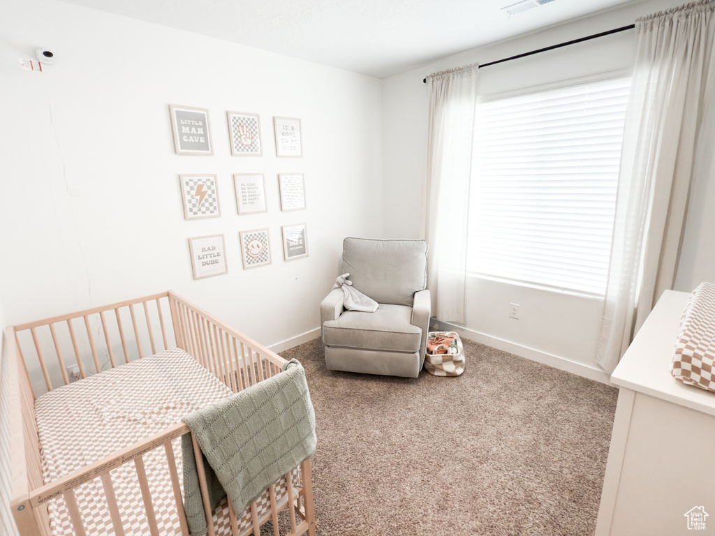 Carpeted bedroom with a crib, baseboards, and visible vents
