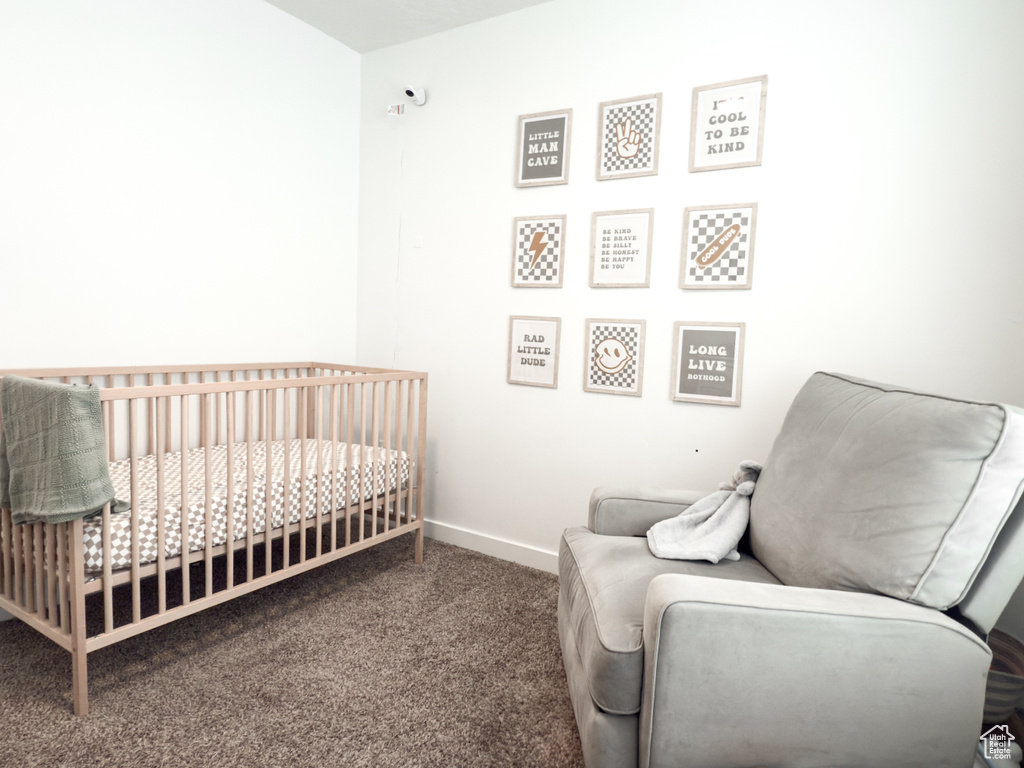 Carpeted bedroom featuring baseboards and a crib