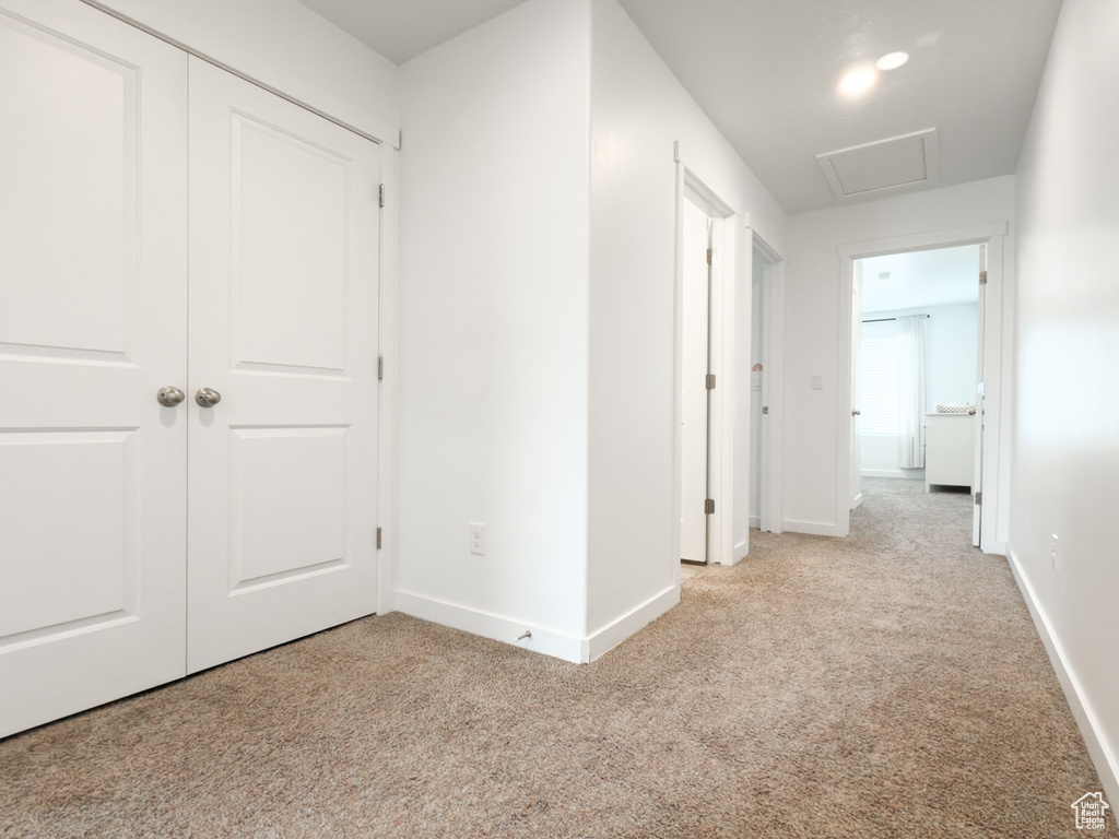 Corridor featuring baseboards and light colored carpet
