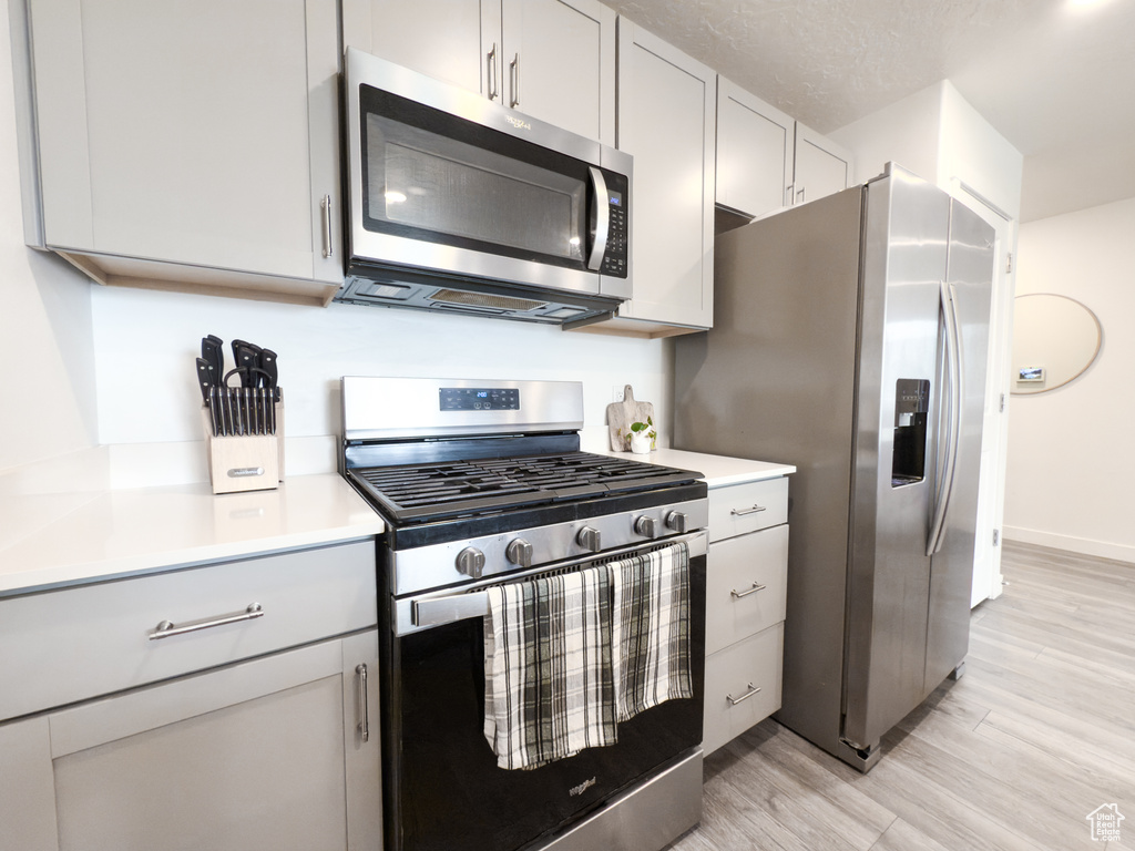 Kitchen featuring light countertops, baseboards, light wood-style floors, and stainless steel appliances