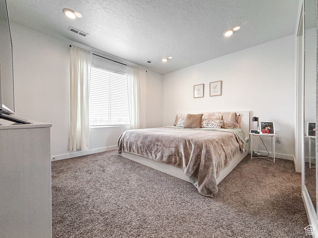 Carpeted bedroom featuring baseboards, recessed lighting, a textured ceiling, and visible vents