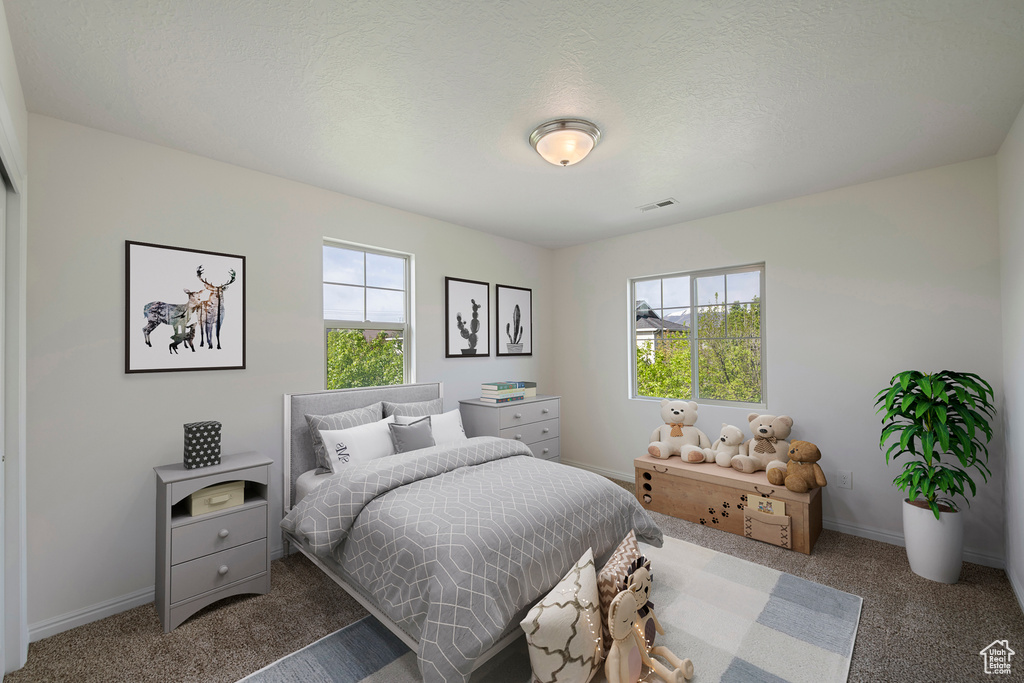 Carpeted bedroom featuring visible vents, multiple windows, and baseboards