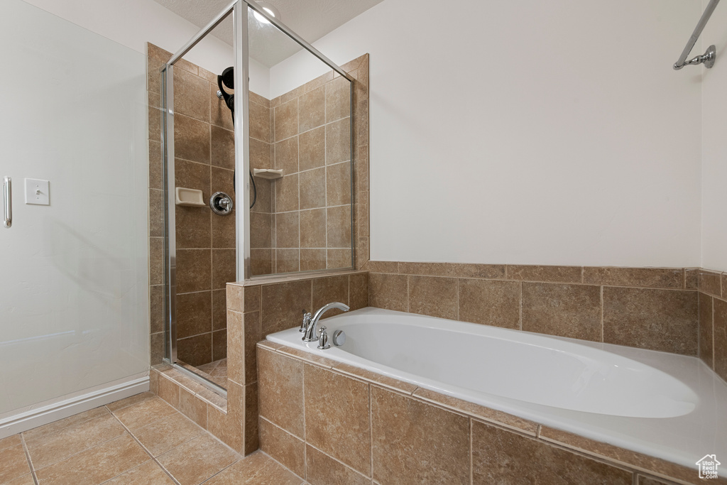 Full bath with tile patterned floors, a bath, and a stall shower