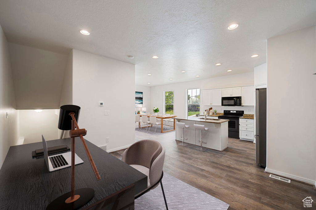 Office area featuring baseboards, visible vents, dark wood-style flooring, and recessed lighting