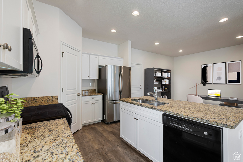 Kitchen with light stone countertops, a sink, a center island with sink, dark wood-type flooring, and black appliances