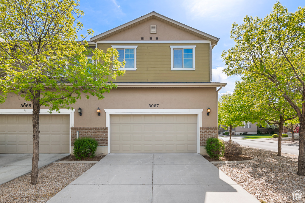 View of front of house featuring stucco siding, concrete driveway, brick siding, and a garage
