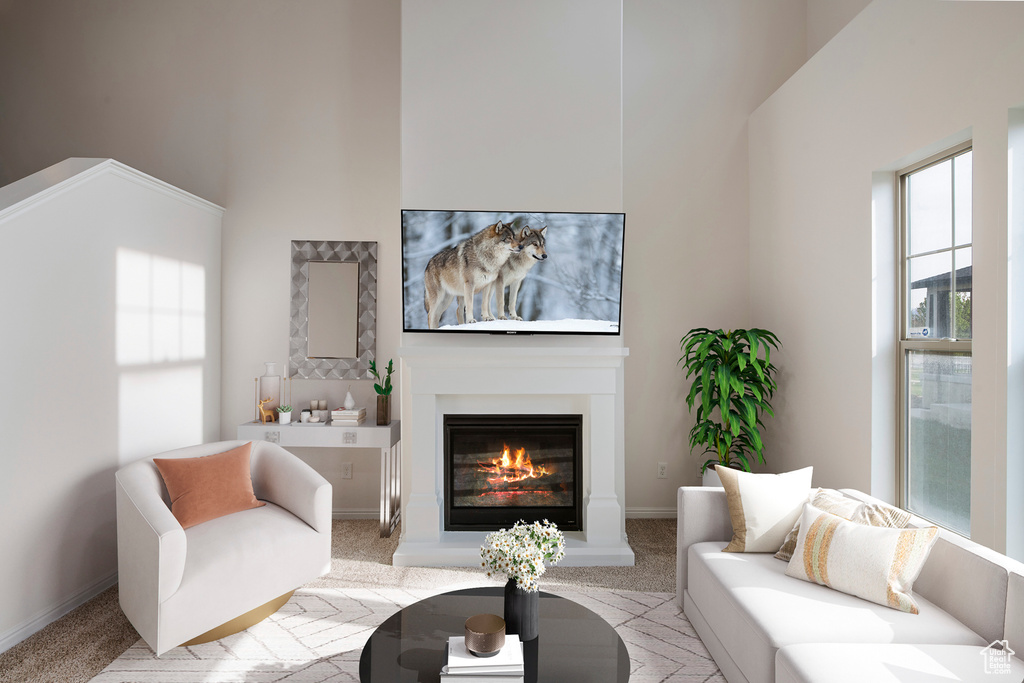 Living room with baseboards, light carpet, a high ceiling, and a glass covered fireplace