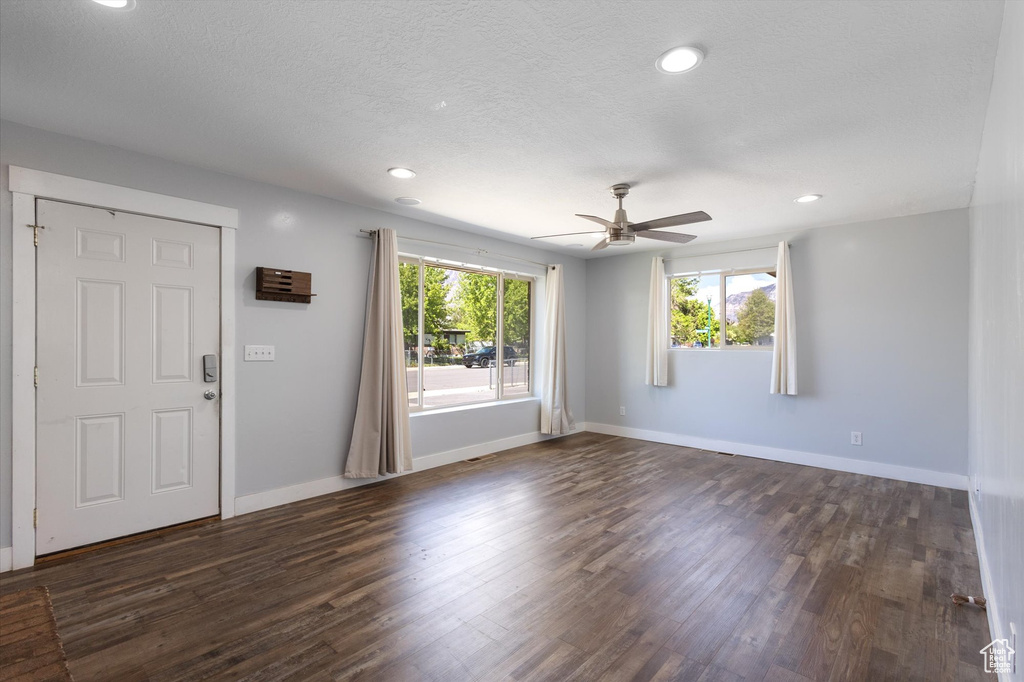 Unfurnished living room with dark wood-type flooring, ceiling fan, baseboards, recessed lighting, and a textured ceiling
