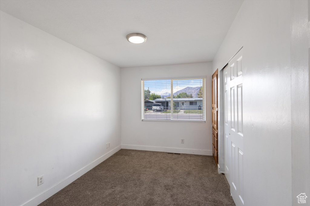 Carpeted spare room featuring baseboards