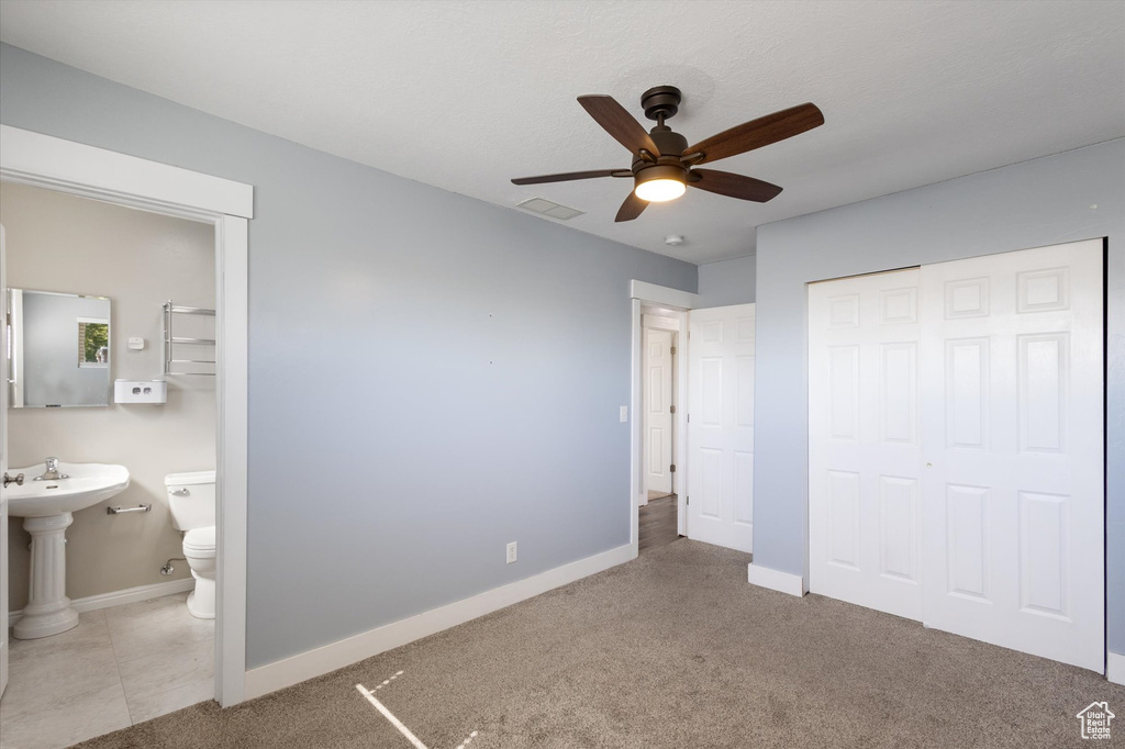 Unfurnished bedroom featuring a closet, baseboards, ensuite bath, and ceiling fan