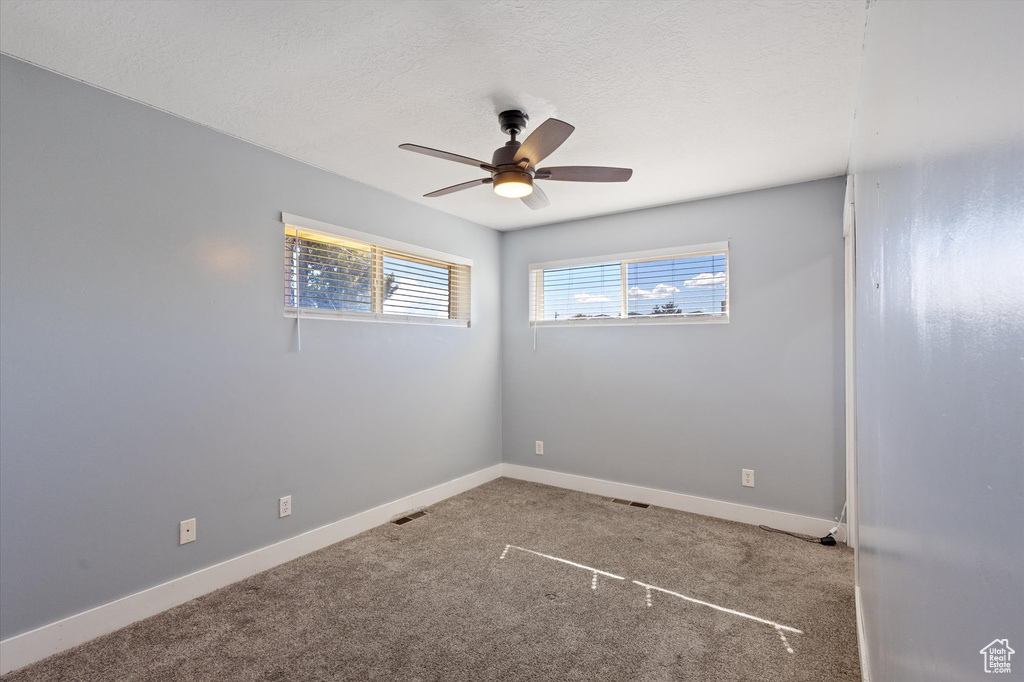 Carpeted empty room with a ceiling fan and baseboards