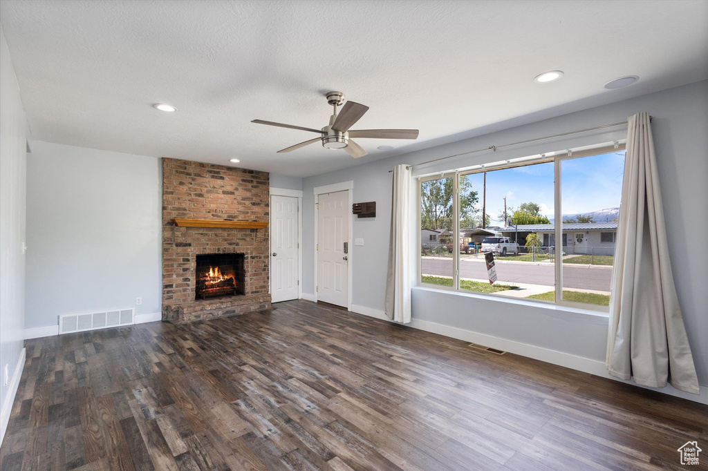Unfurnished living room with a ceiling fan, a brick fireplace, baseboards, dark wood-style flooring, and recessed lighting