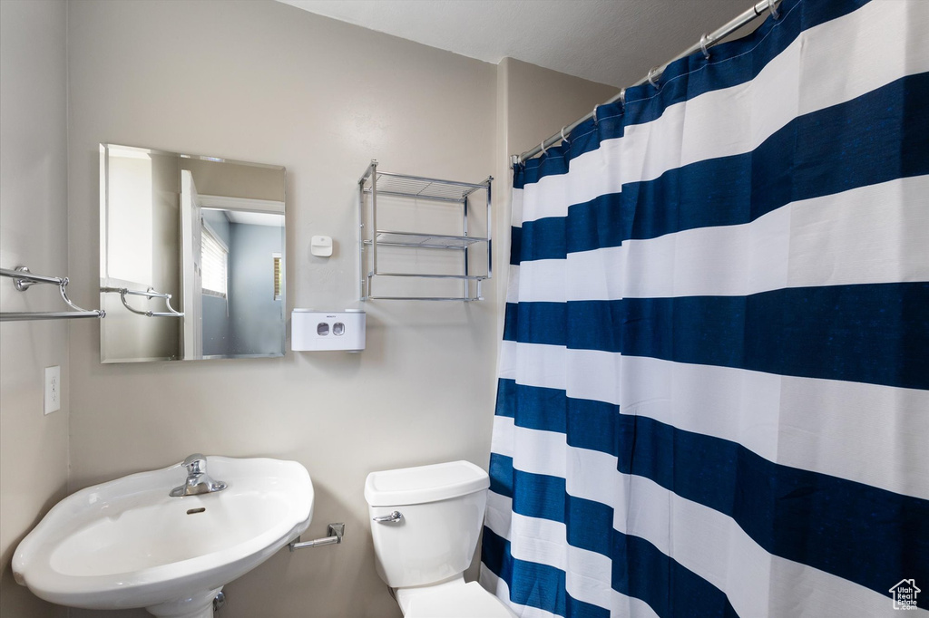 Full bathroom featuring a sink, toilet, and curtained shower