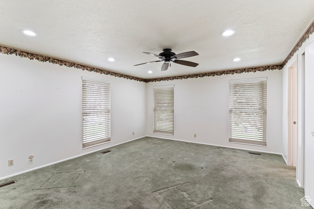 Spare room with ceiling fan, visible vents, plenty of natural light, and carpet