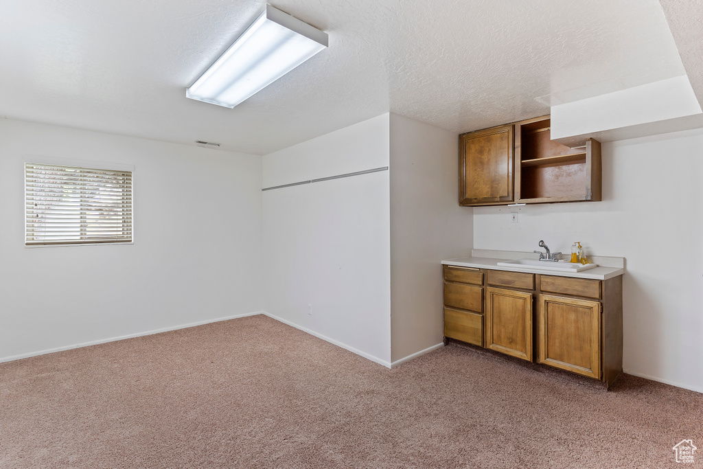 Bar with baseboards, a sink, visible vents, and light carpet