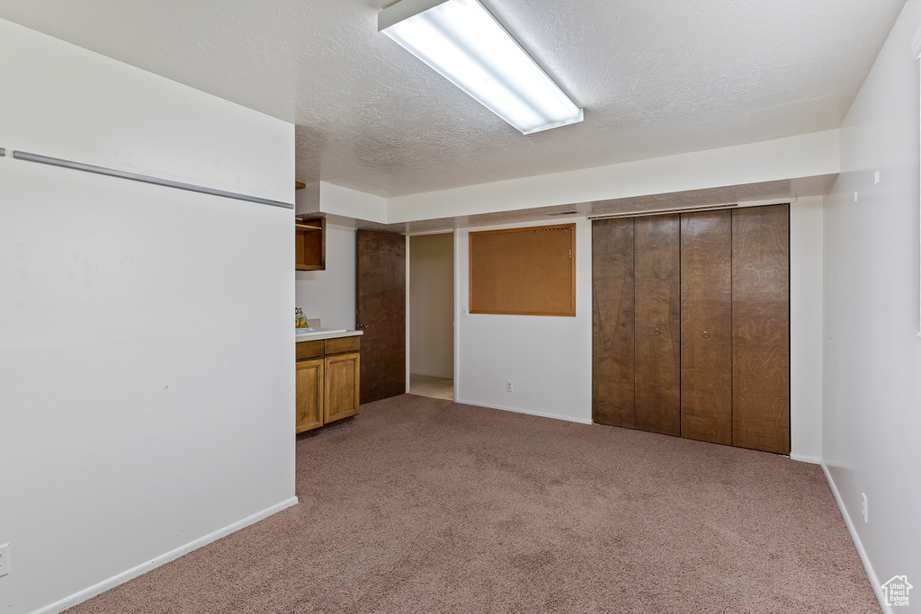 Interior space with a textured ceiling, light carpet, and baseboards