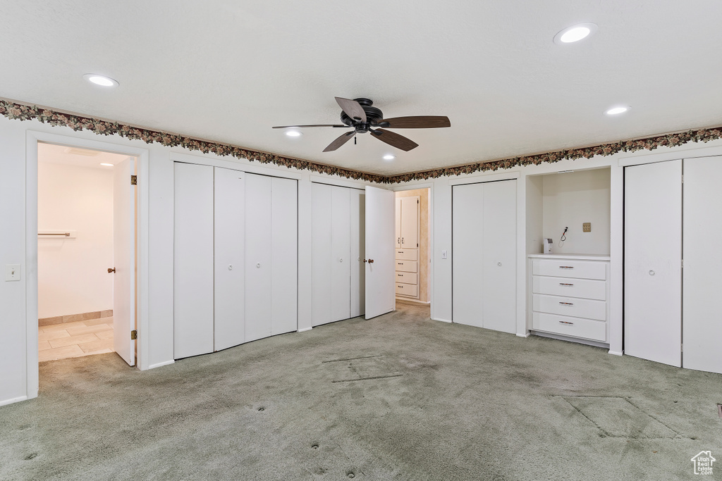 Unfurnished bedroom featuring carpet flooring, recessed lighting, multiple closets, and ensuite bath