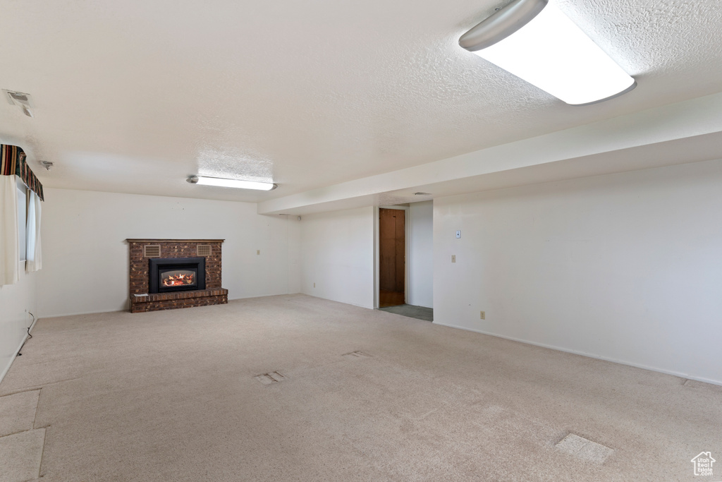 Finished below grade area with carpet floors, a textured ceiling, and a fireplace