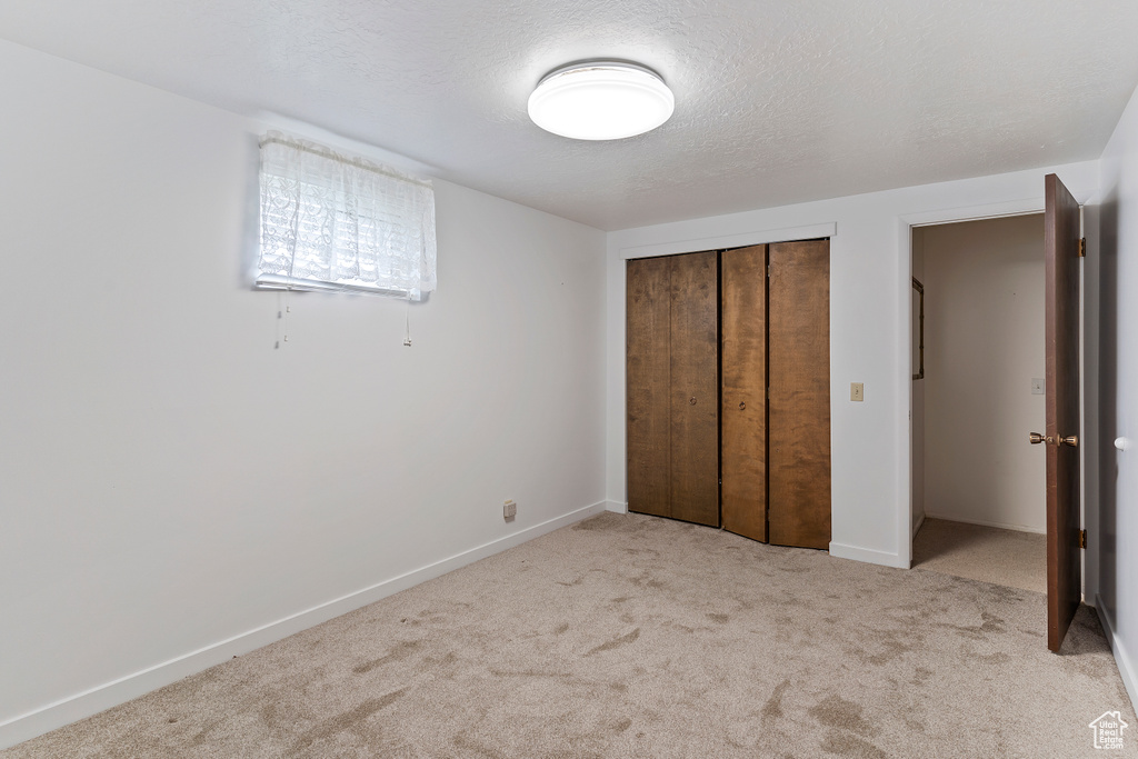 Unfurnished bedroom with carpet floors, a textured ceiling, baseboards, and a closet