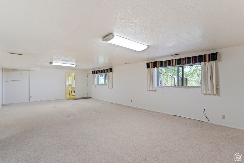Spare room with light colored carpet, baseboards, a wealth of natural light, and visible vents