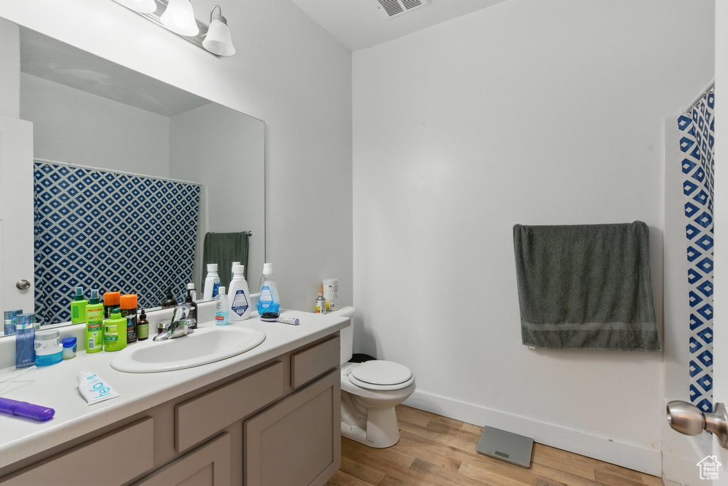 Full bath with visible vents, baseboards, toilet, wood finished floors, and vanity