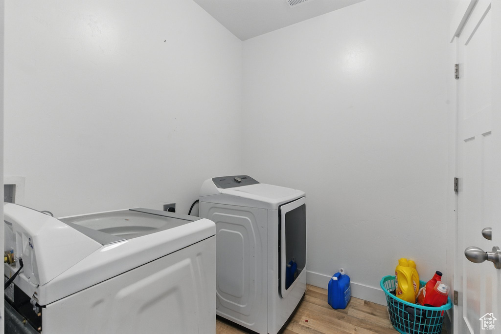 Laundry area with baseboards, light wood-style floors, laundry area, and washing machine and dryer