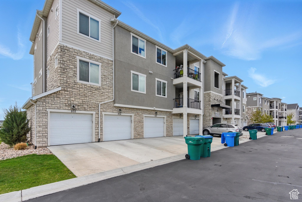 View of building exterior featuring a residential view, concrete driveway, and a garage