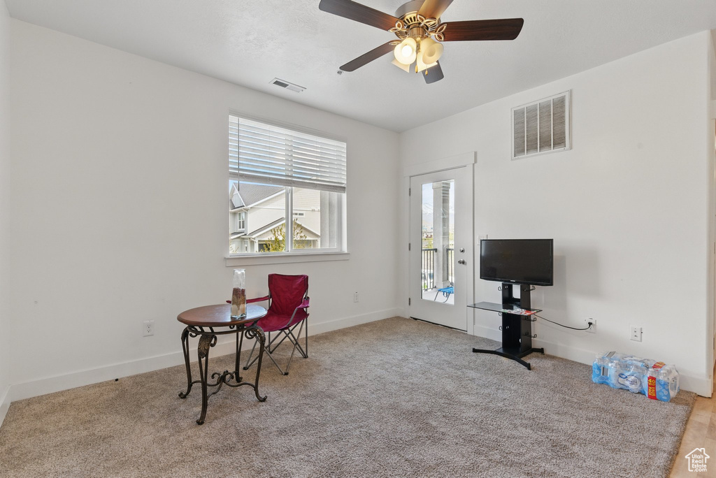Living area featuring baseboards, visible vents, ceiling fan, and carpet floors