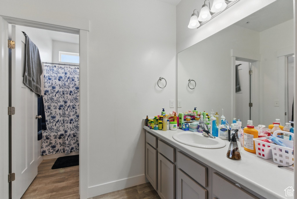 Bathroom featuring baseboards, wood finished floors, a shower with shower curtain, and vanity