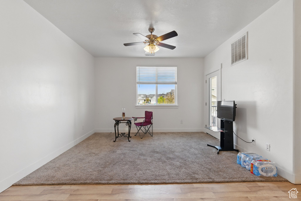 Living area with ceiling fan, visible vents, carpet, baseboards, and wood finished floors