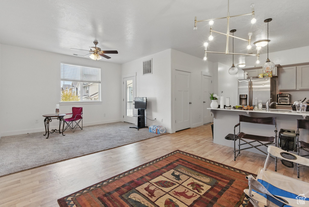 Living area featuring visible vents, ceiling fan, light wood-style flooring, and baseboards
