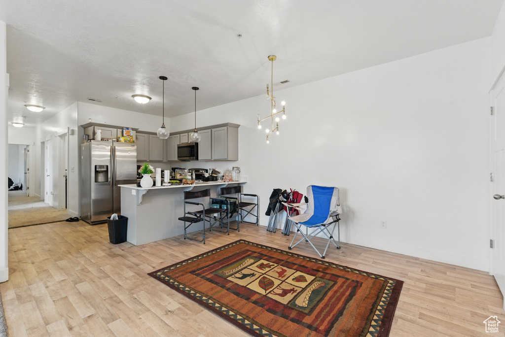Kitchen with stainless steel appliances, a kitchen breakfast bar, light wood-style flooring, a peninsula, and gray cabinetry