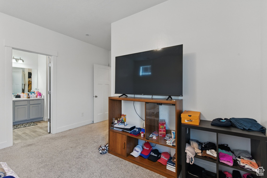 Bedroom featuring ensuite bath, light carpet, and baseboards