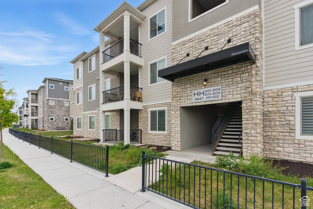 View of building exterior featuring fence, stairway, and a residential view