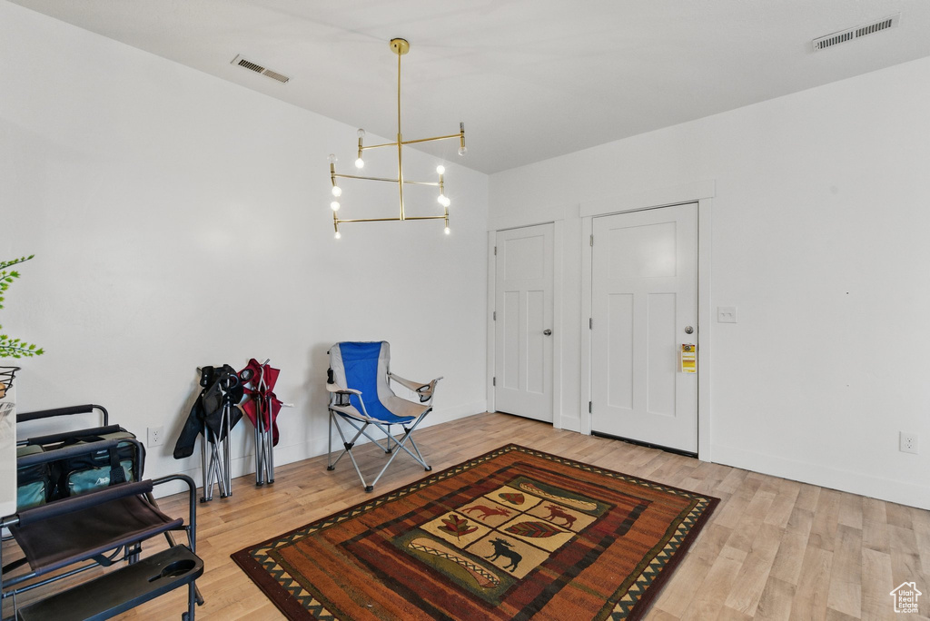 Entrance foyer with wood finished floors, visible vents, and a chandelier