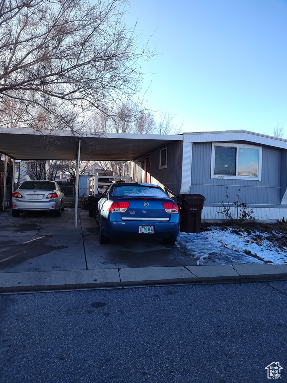 View of front of house with concrete driveway and a carport