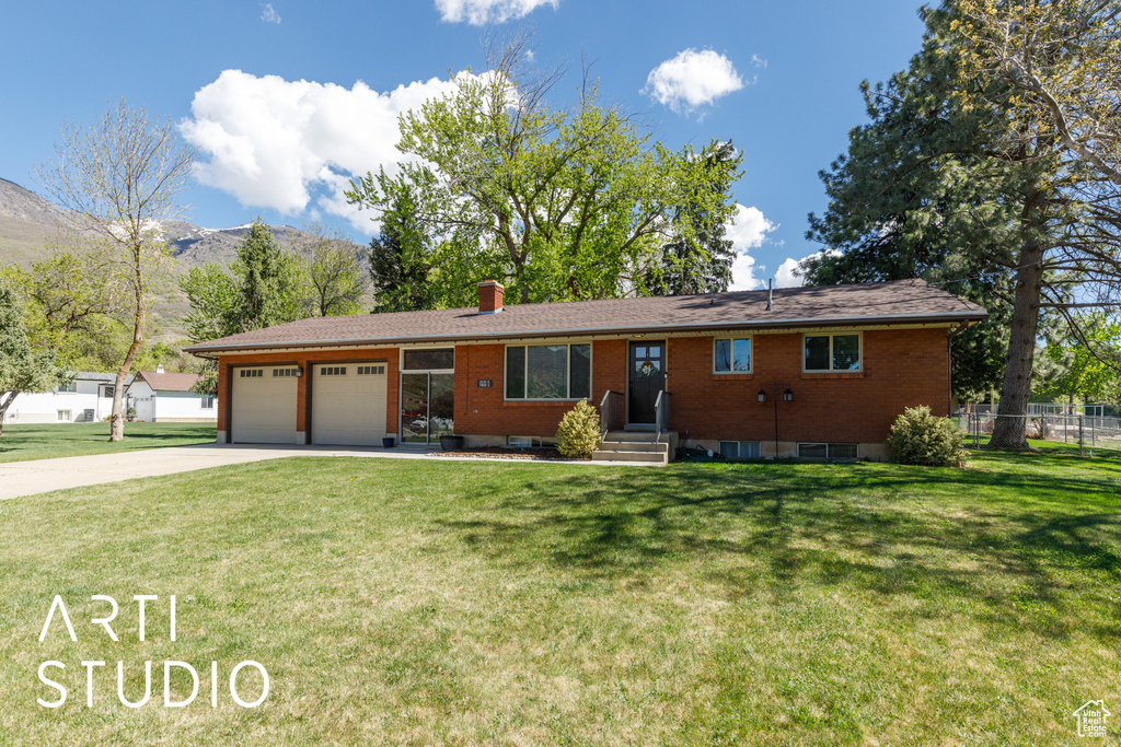 Ranch-style home with an attached garage, a front lawn, a mountain view, and concrete driveway