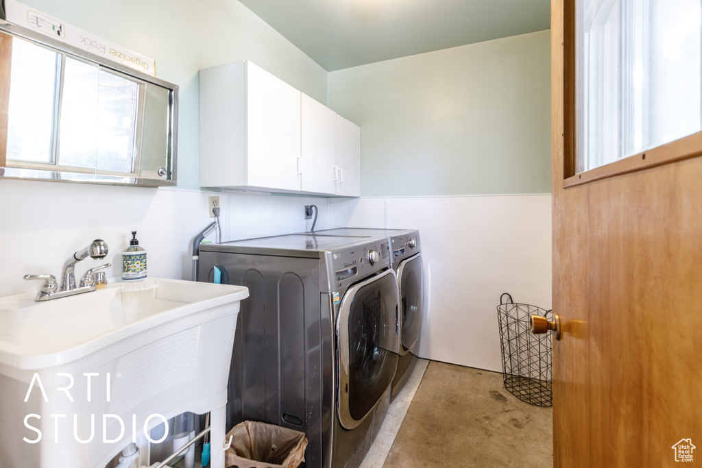 Clothes washing area featuring a sink, cabinet space, and independent washer and dryer