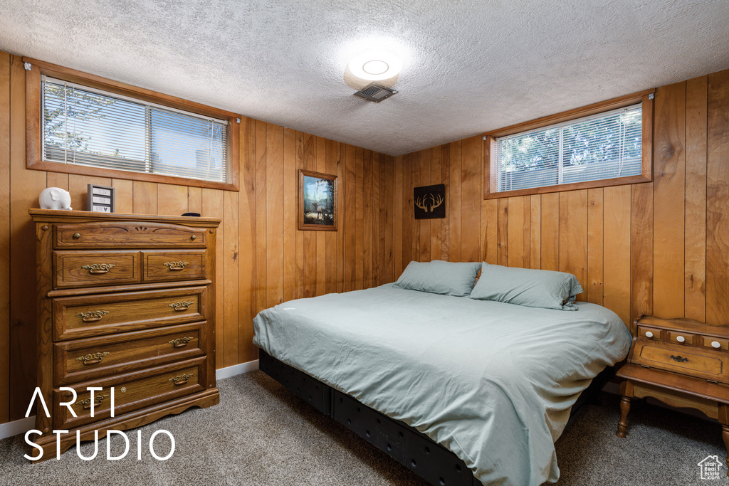 Bedroom with visible vents, wood walls, a textured ceiling, and carpet floors